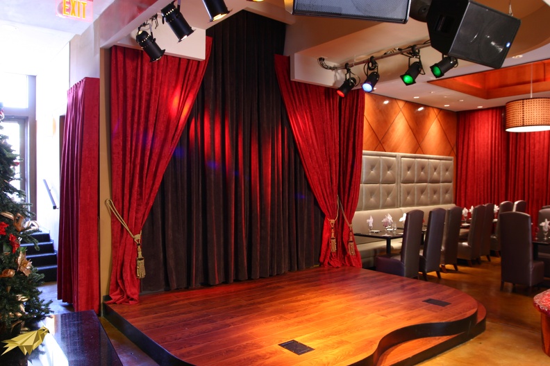 We updated this stage with a custom curved shape and added cable access ports for front stage performances. Thick velvet curtains help to dampen hard echo sounds and make for a very warm, intimate atmosphere. Custom Stage at Cosmo Rouge.JPG